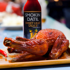 Smokin Datil Sweet Heat bottle beside tacos and burritos, versatile on meals.
