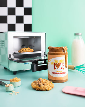 Spread The Love almond butter spoon and tub on a tidy kitchen counter
