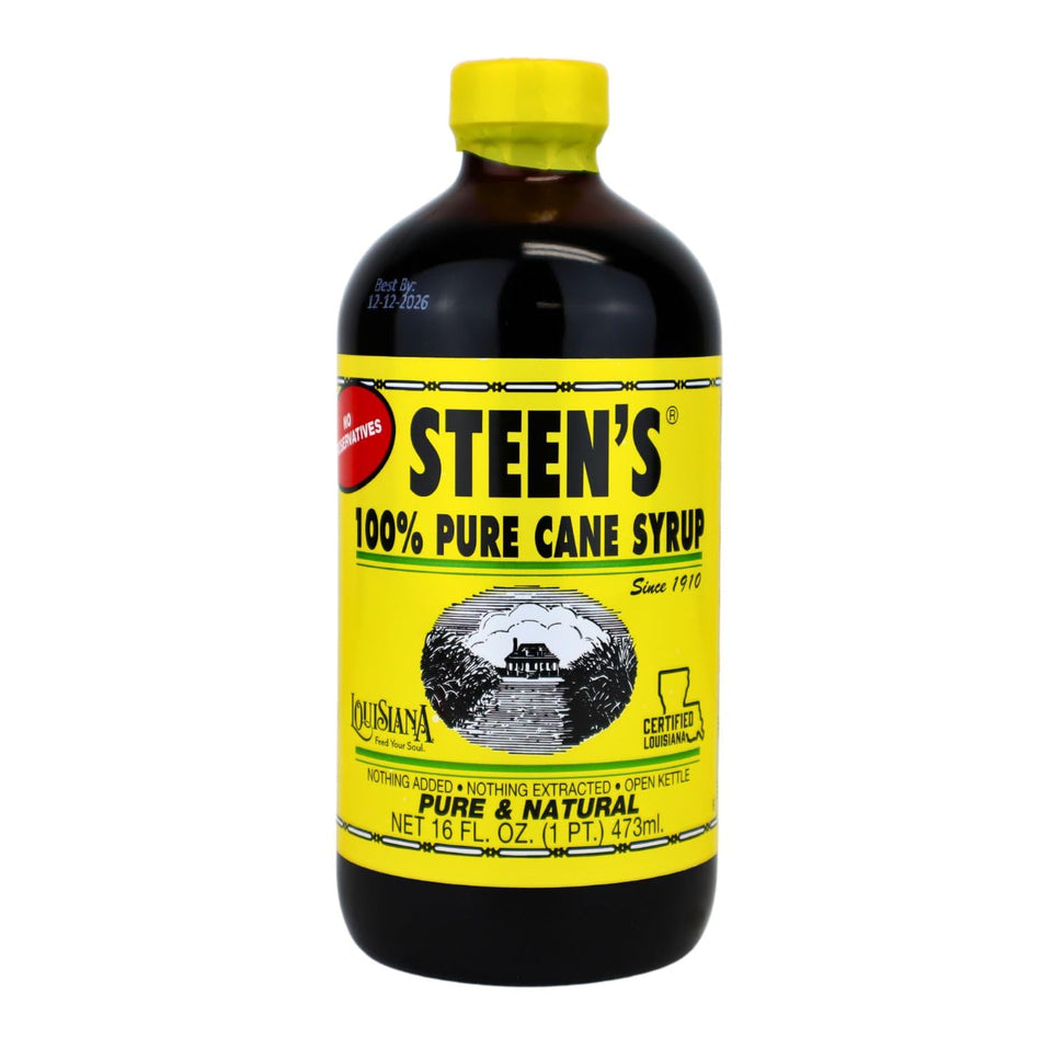 Steen's Cane Syrup bottle with open kettle in the background, rich flavor ready for traditional dishes.