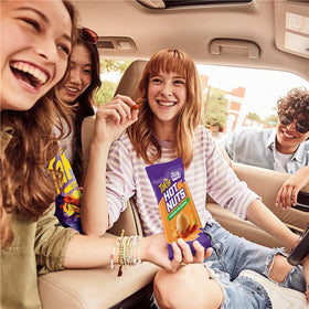 On-the-go Takis Nacho Xplosion Hot Nuts being grabbed as a quick snack.