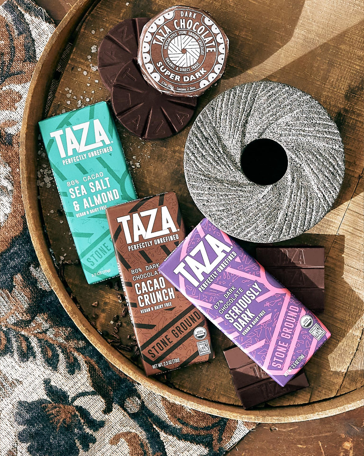 Granite millstone imagery underscores the stone-ground chocolate process.