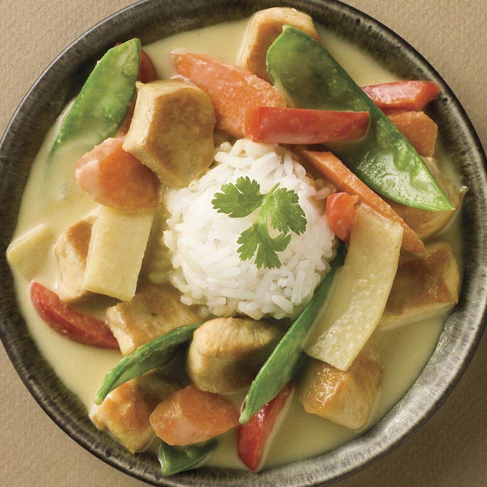 Thai Kitchen green curry paste stirred into a hot skillet for a vibrant stir-fry.