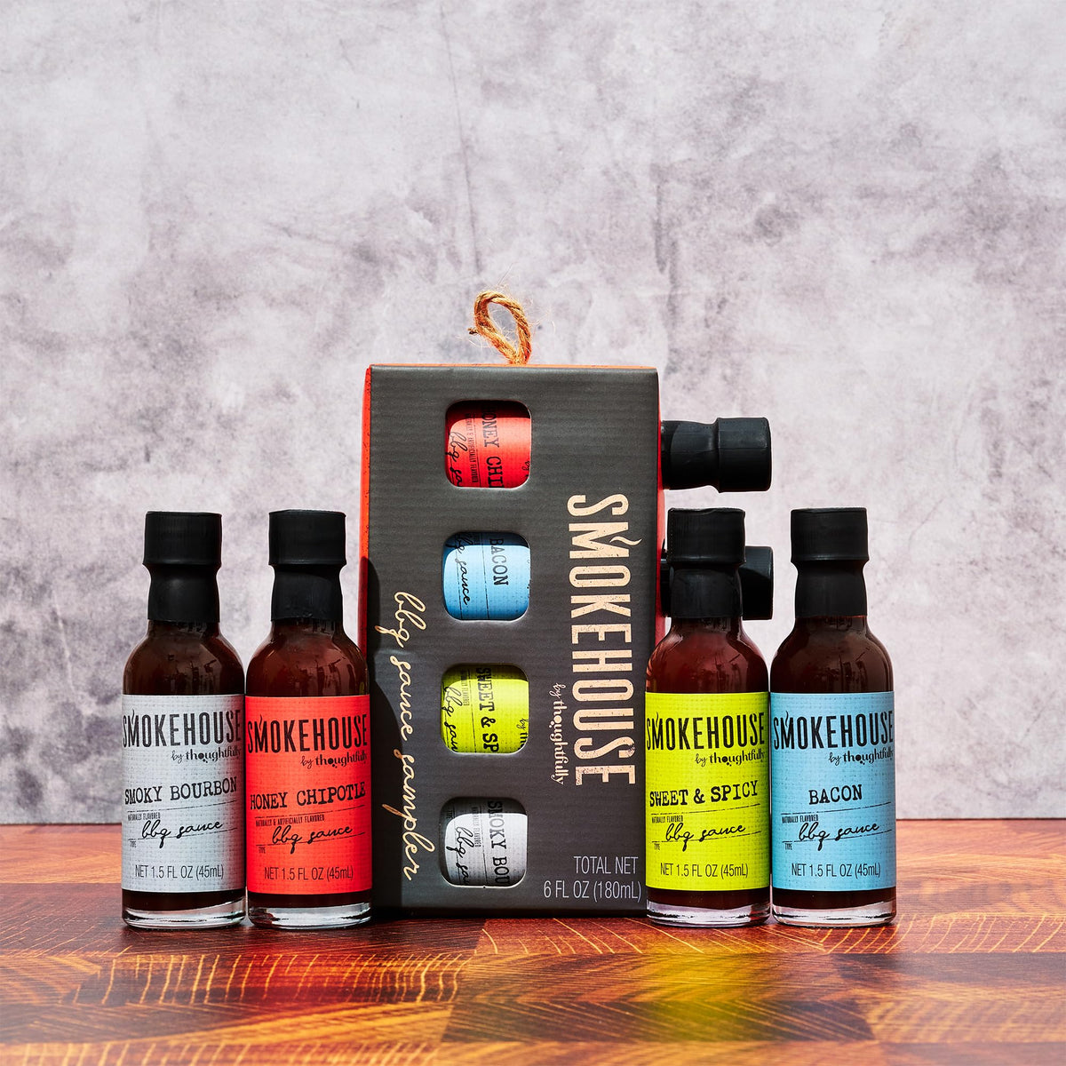 Thoughtfully Smokehouse four-bottle sampler on a grill-ready setup.