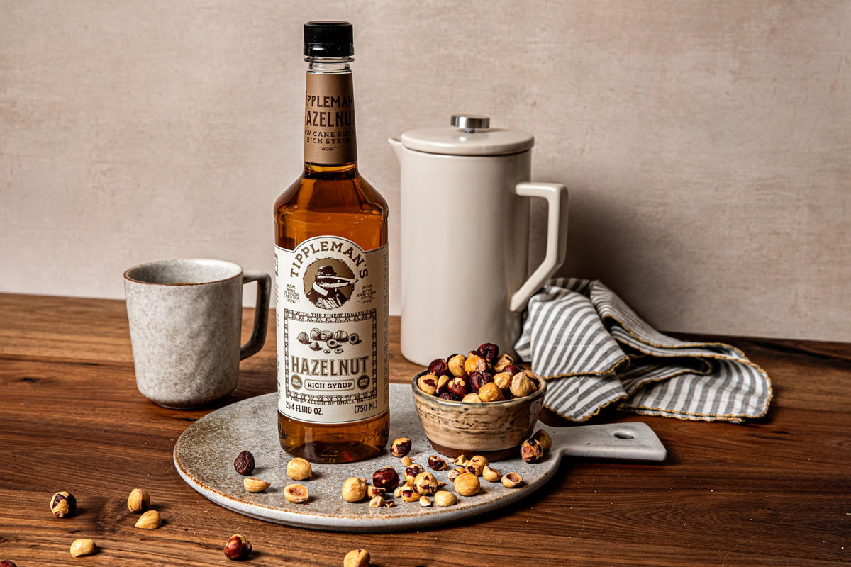 Pouring Tippleman's Hazelnut Syrup into coffee for a smooth flavor.
