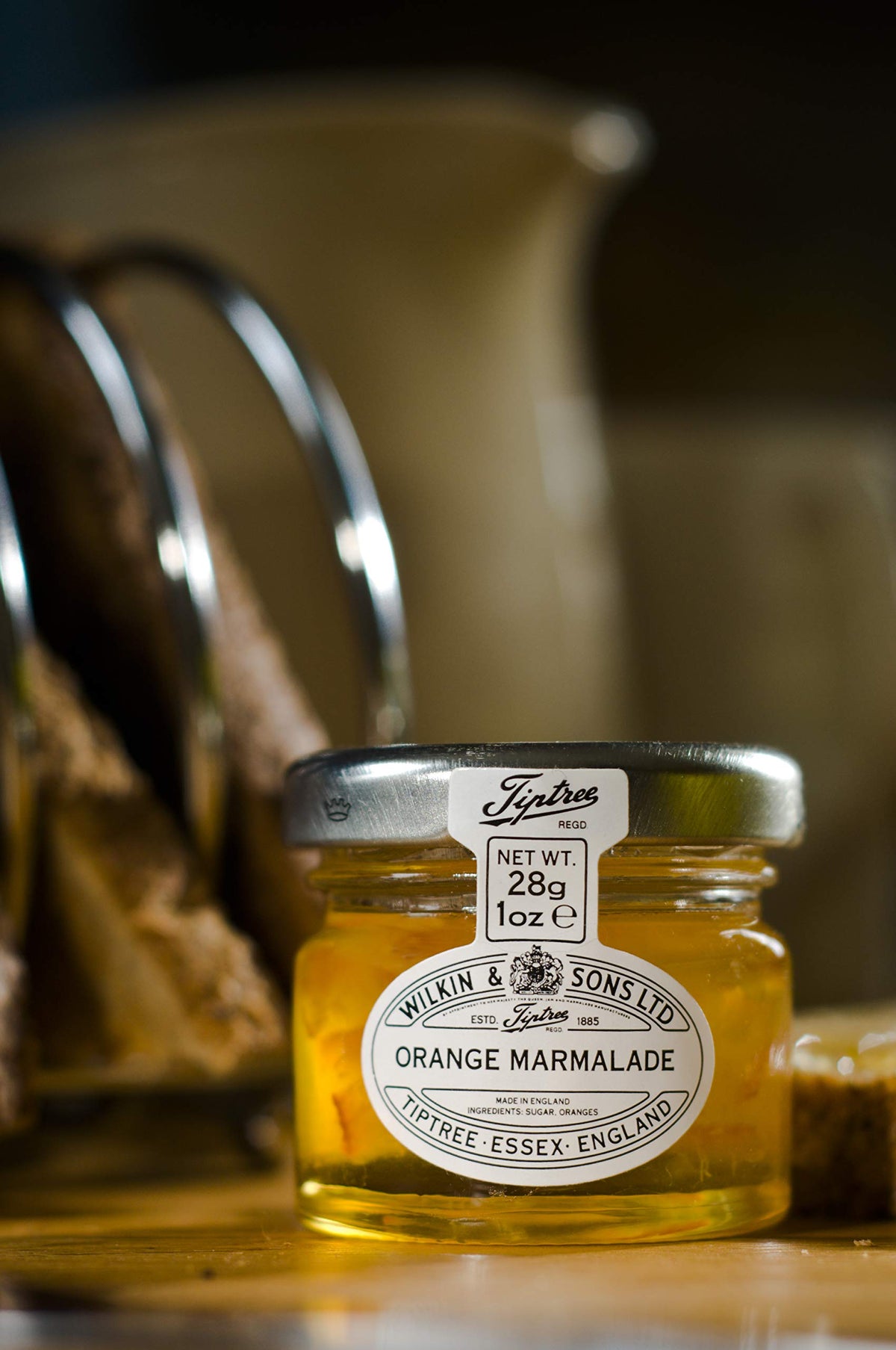 Tiptree Orange Marmalade Minis golden glaze on counter, inviting aroma.