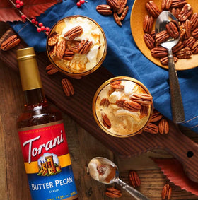 Pouring Torani Butter Pecan Syrup into a latte for depth.