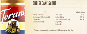 Torani Cheesecake Syrup tilted bottle beside a cup signals flavor elevation.