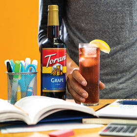 Torani grape syrup poured into coffee for a fruity twist