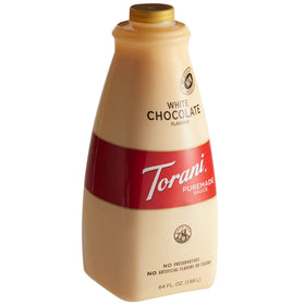 Torani Puremade White Chocolate sauce bottle pouring into a latte, enriching the cup with creamy sweetness.