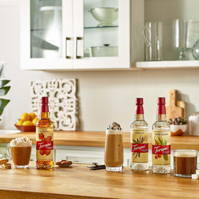 Torani Puremade Vanilla syrup bottle beside hot coffee for flavor boost