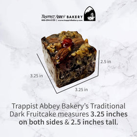 Trappist Abbey fruitcake on a wooden platter with brandy glass, cozy holiday mood.