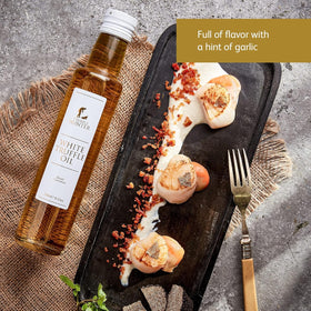 TruffleHunter white truffle oil drizzle drops finishing a dish.
