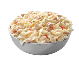 Cooked vegetables stirred into Tuna Helper dish.