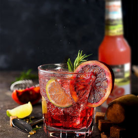 Tuscanini Organic Blood Orange Soda glass with ice, showcasing vibrant color and natural flavor.