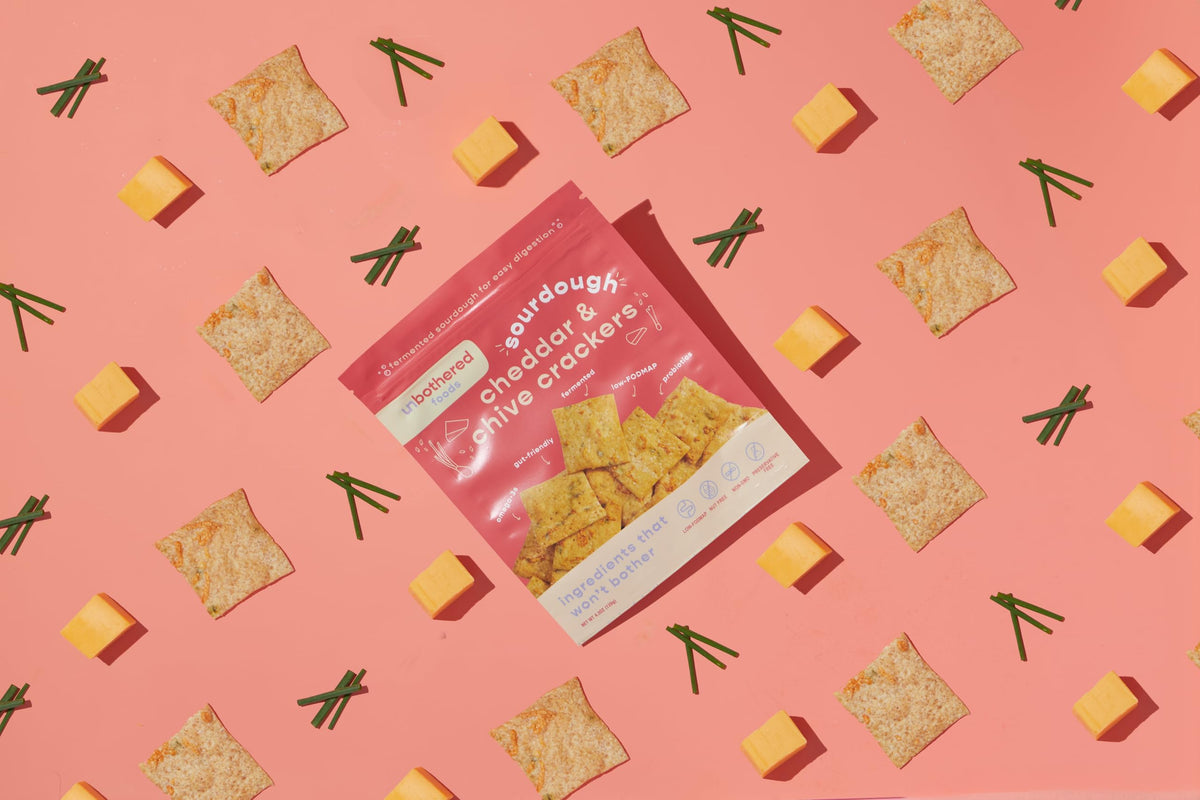 Crackers dipped in honey on a tasting board with cheese.