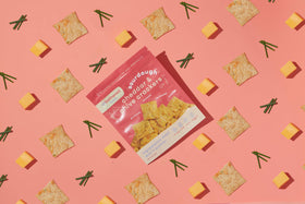 Crackers dipped in honey on a tasting board with cheese.
