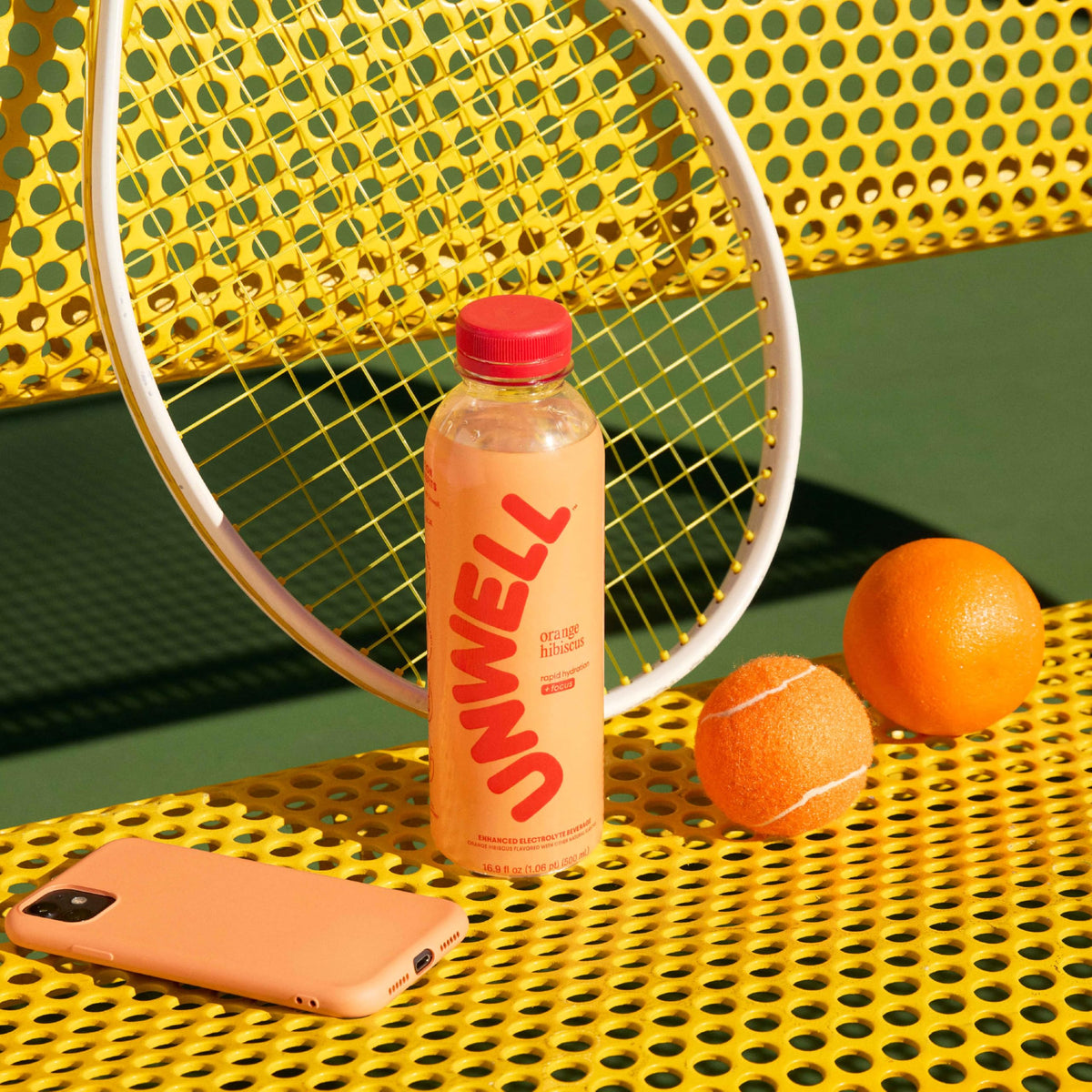 Unwell Hydration orange hibiscus color in a glass emphasizes refreshing flavor and focus.