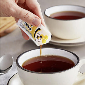 Vallary honey packets in open packaging on kitchen counter for easy sweetening.