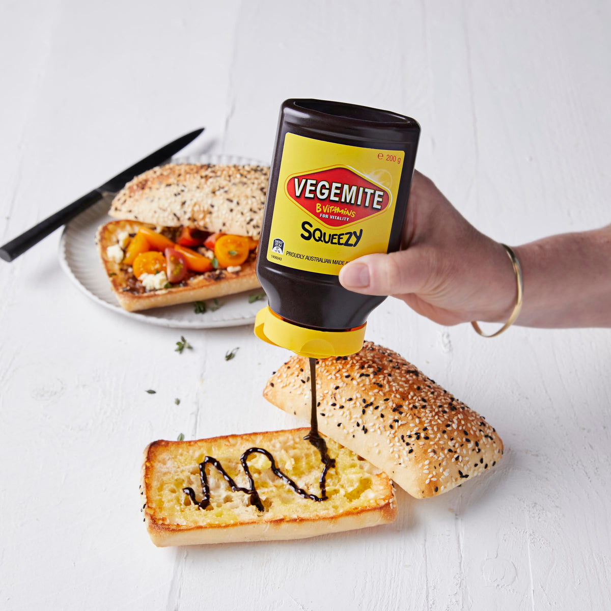 Vegemite Squeezy bottle spread on crackers for a convenient snack.