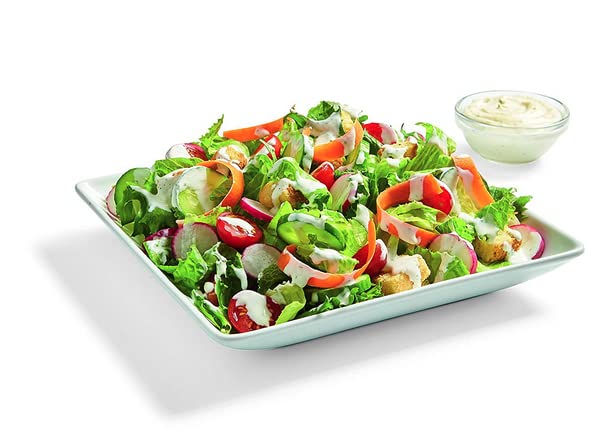Watkins dressing being poured over a salad for quick dressing.