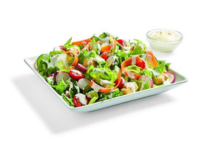 Watkins dressing being poured over a salad for quick dressing.