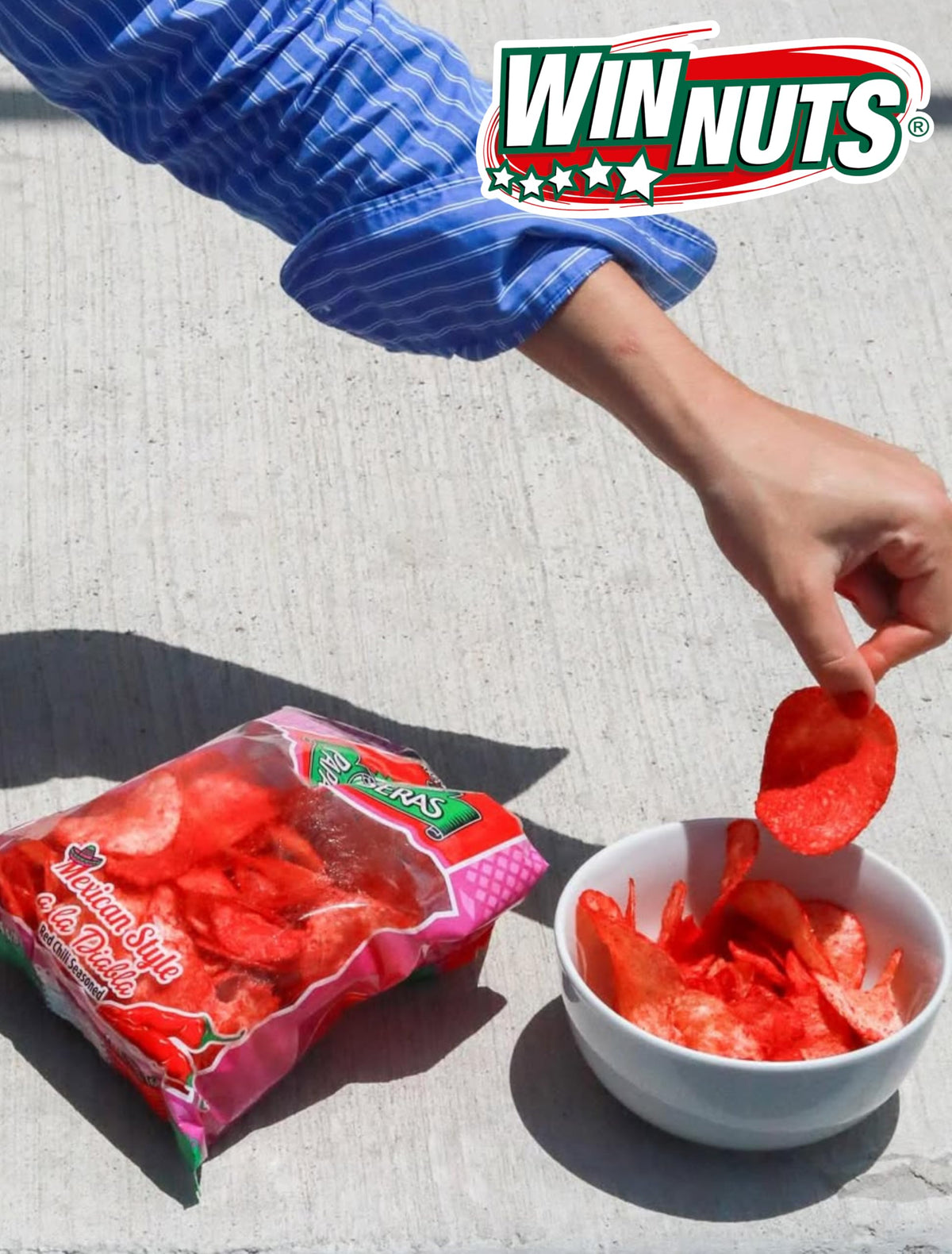 Hand holding a WINNUTS A la Diabla chip, ready to snack.