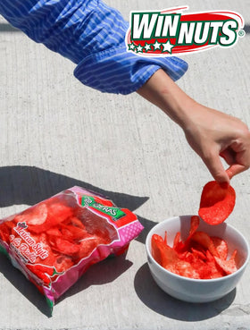 Hand holding a WINNUTS A la Diabla chip, ready to snack.