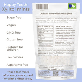 Xylify Happy Teeth mints on table beside glass for everyday breath refreshment.