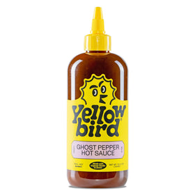 Yellowbird Ghost Pepper hot sauce bottle on table ready to spice up meals.