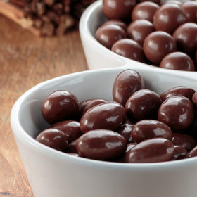 Yupik dark chocolate coconut almonds coating close-up, smooth shell over whole nuts.